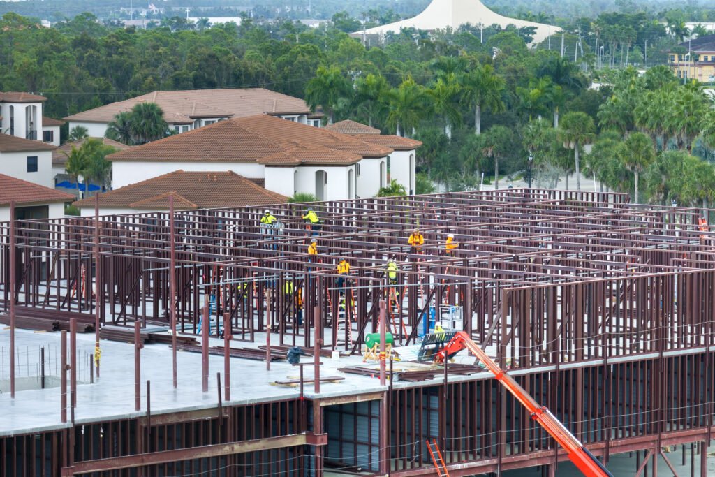 Construction site with hardhat workers assembling metal frame walls.