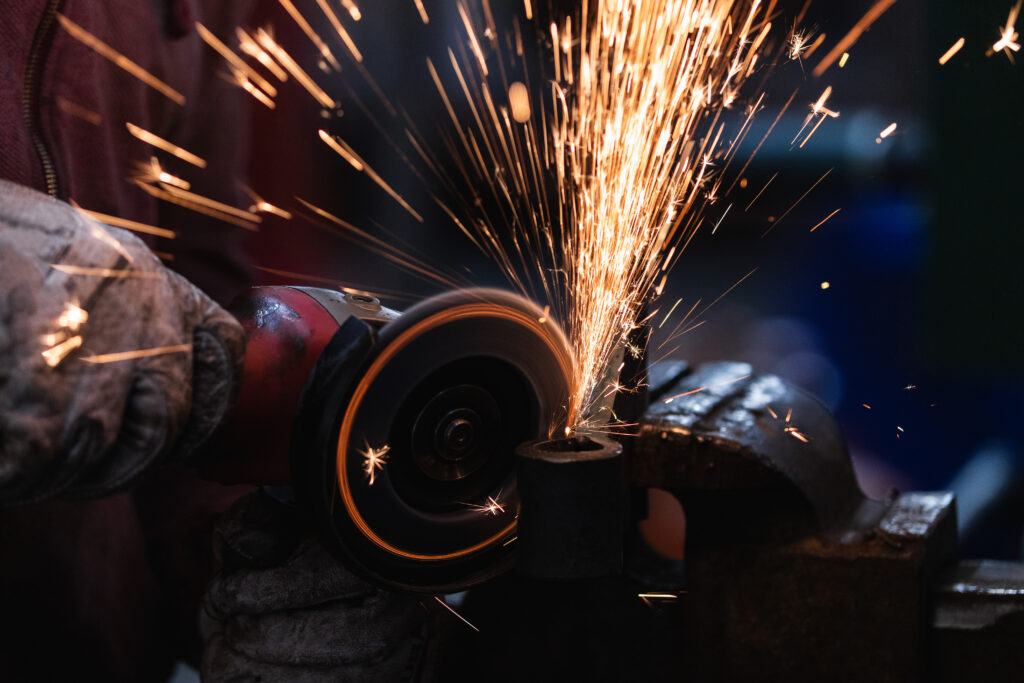 Craftsman grinding metal with grinder in vice